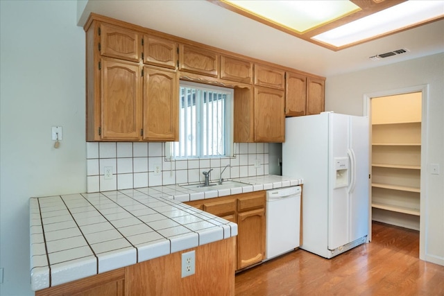 kitchen with sink, white appliances, tile countertops, and backsplash