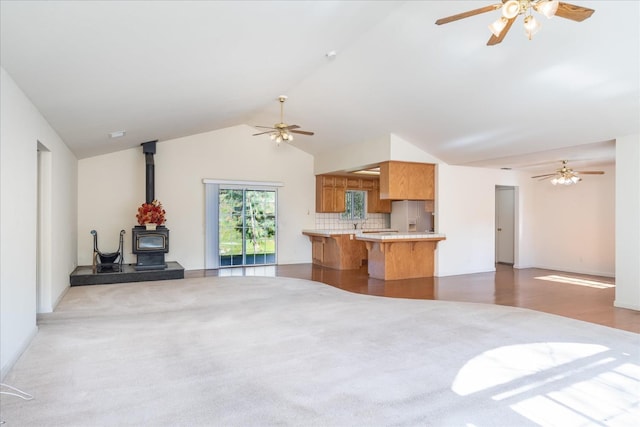 living room with vaulted ceiling, a wood stove, and ceiling fan