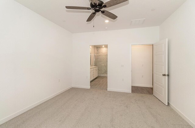 unfurnished bedroom with connected bathroom, light colored carpet, and ceiling fan