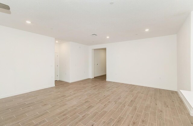 unfurnished room with light hardwood / wood-style flooring and a textured ceiling