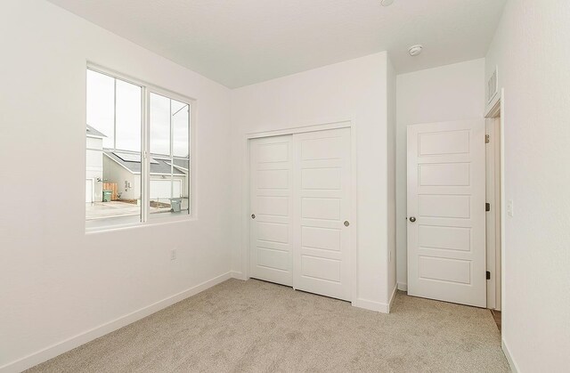 unfurnished bedroom with multiple windows, light colored carpet, and a closet