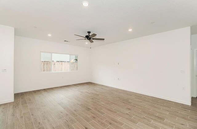 spare room with ceiling fan, a textured ceiling, and light wood-type flooring