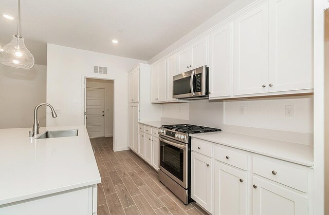 kitchen with white cabinetry, appliances with stainless steel finishes, sink, and pendant lighting