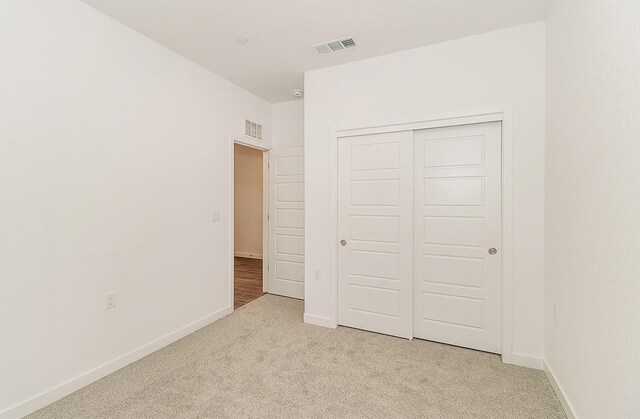 unfurnished bedroom featuring light colored carpet and a closet