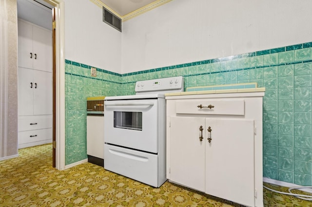 kitchen with white electric range, tile walls, and white cabinets