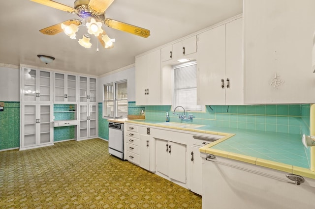 kitchen with sink, white dishwasher, white cabinets, ceiling fan, and backsplash