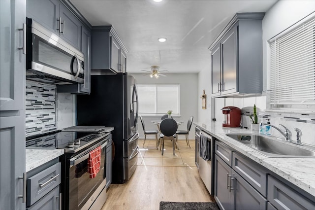 kitchen with gray cabinets, appliances with stainless steel finishes, tasteful backsplash, sink, and ceiling fan