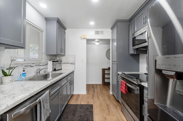 kitchen with light hardwood / wood-style floors, appliances with stainless steel finishes, gray cabinets, and sink