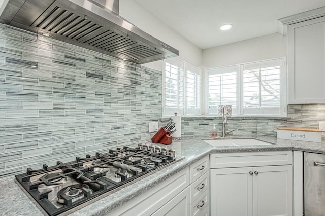 kitchen with sink, a wealth of natural light, stainless steel gas cooktop, white cabinets, and wall chimney exhaust hood