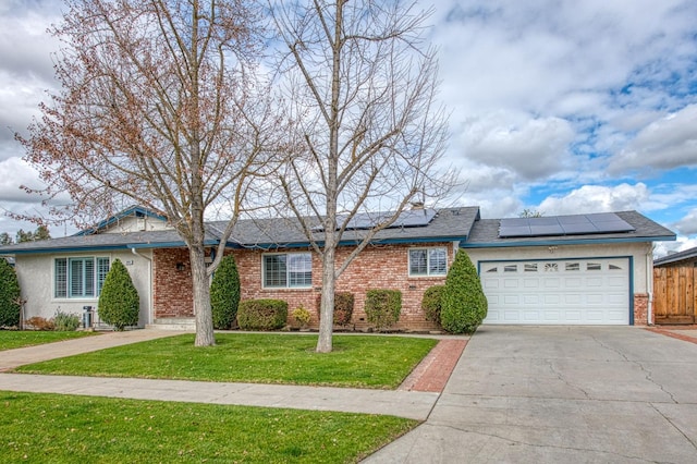 ranch-style home featuring a garage, solar panels, and a front lawn