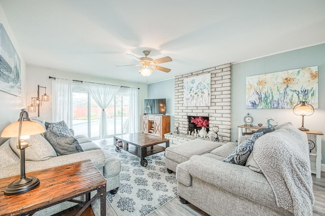 living room with a brick fireplace, light hardwood / wood-style floors, and ceiling fan