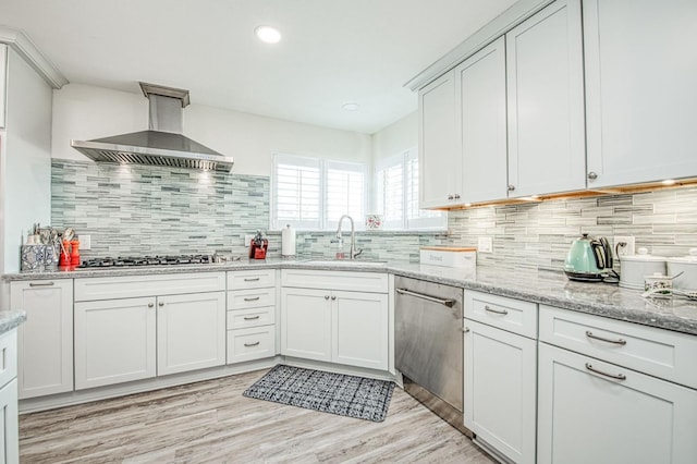 kitchen featuring sink, light wood-type flooring, stainless steel appliances, light stone countertops, and exhaust hood