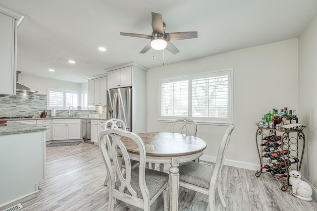 dining space featuring sink, light hardwood / wood-style flooring, and ceiling fan