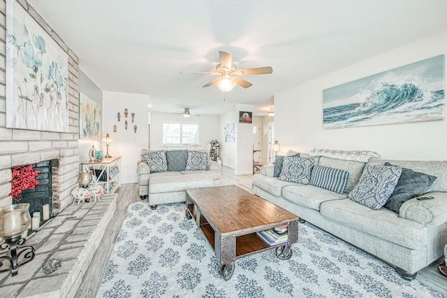 living room featuring ceiling fan, a fireplace, and light wood-type flooring