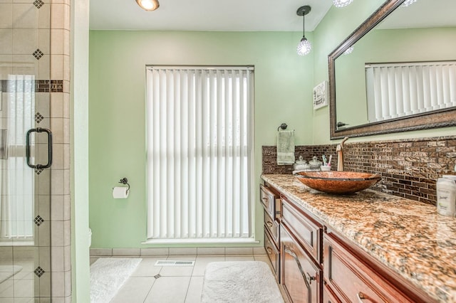 bathroom featuring tasteful backsplash, vanity, tile patterned floors, and walk in shower