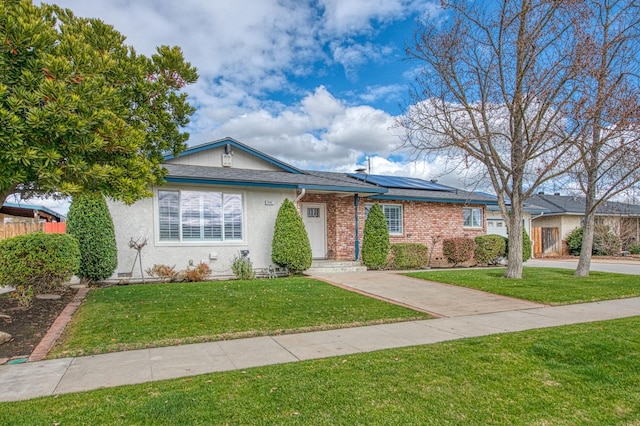 view of front of property featuring a front lawn and solar panels