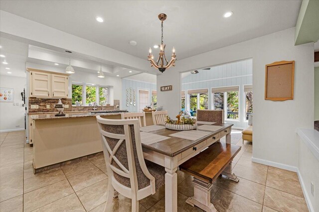 dining room with an inviting chandelier, light tile patterned floors, and a tray ceiling