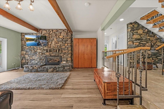 living room featuring beamed ceiling, a fireplace, and light hardwood / wood-style floors