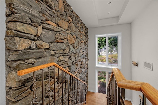 stairs featuring a tray ceiling and hardwood / wood-style flooring