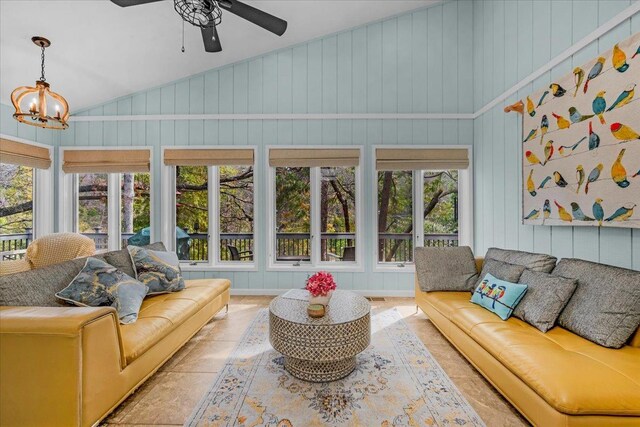 sunroom featuring ceiling fan with notable chandelier, plenty of natural light, and vaulted ceiling