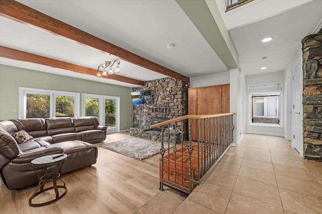 tiled living room featuring beamed ceiling, a fireplace, and a notable chandelier