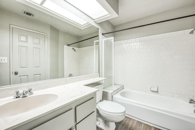 full bath with visible vents, toilet, wood finished floors, a skylight, and vanity