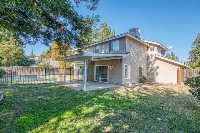 rear view of house with a lawn, fence, cooling unit, a fenced in pool, and a patio area