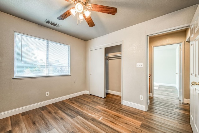 unfurnished bedroom with a closet, visible vents, baseboards, and wood finished floors