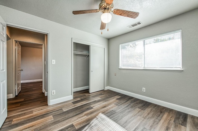 unfurnished bedroom with a closet, visible vents, baseboards, and wood finished floors