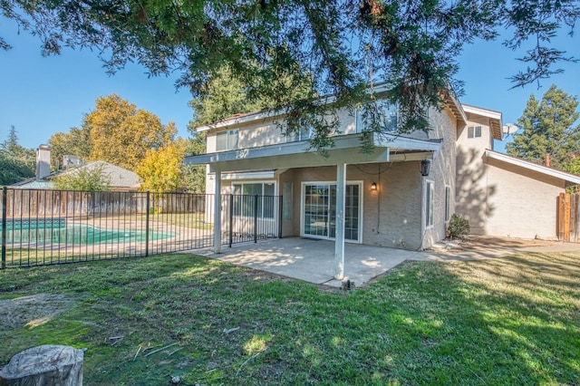 rear view of house with stucco siding, a lawn, a patio, and fence