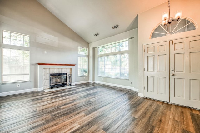 unfurnished living room featuring visible vents, baseboards, a tile fireplace, wood finished floors, and high vaulted ceiling