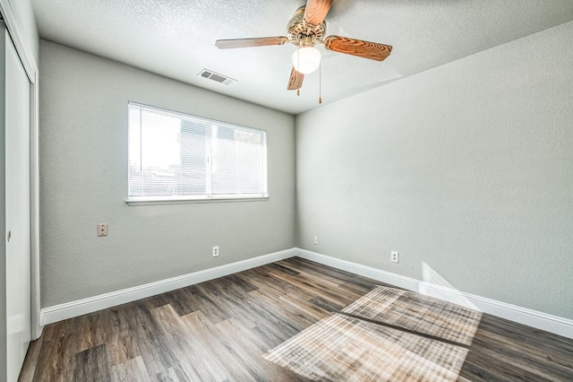 unfurnished room featuring a ceiling fan, wood finished floors, visible vents, baseboards, and a textured ceiling