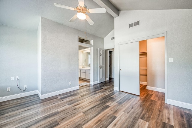 unfurnished bedroom with visible vents, baseboards, beamed ceiling, wood finished floors, and a closet