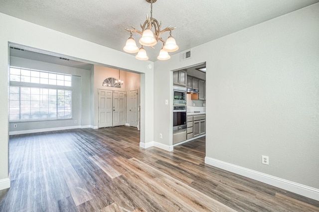 unfurnished dining area with visible vents, baseboards, an inviting chandelier, and dark wood-style flooring