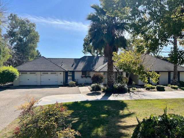 view of front of property featuring aphalt driveway, a garage, and a front lawn