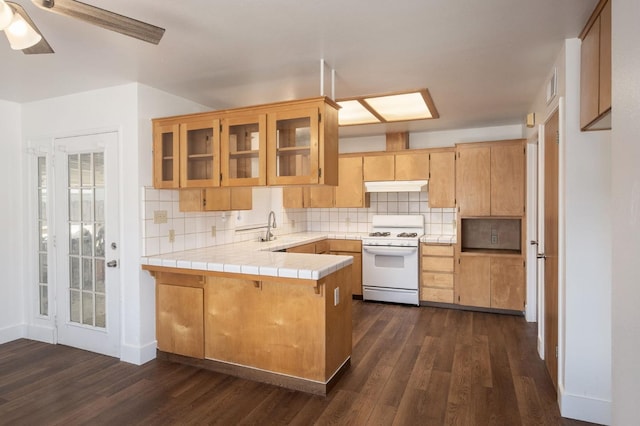 kitchen with sink, white gas stove, tile countertops, kitchen peninsula, and ceiling fan