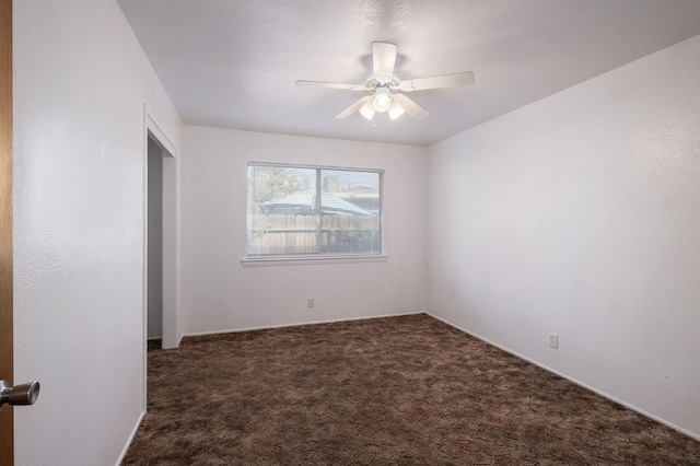 empty room with ceiling fan and dark carpet