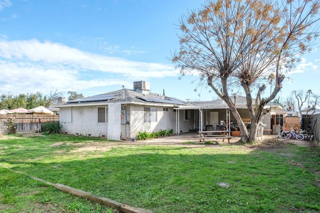 back of property featuring a lawn, a patio, and solar panels