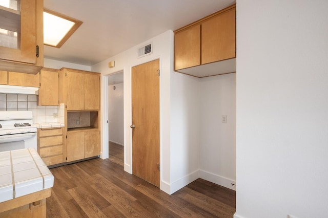 kitchen with white gas range, tile counters, backsplash, and dark hardwood / wood-style flooring