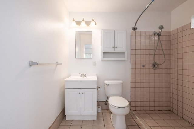 bathroom featuring a tile shower, vanity, tile patterned flooring, and toilet