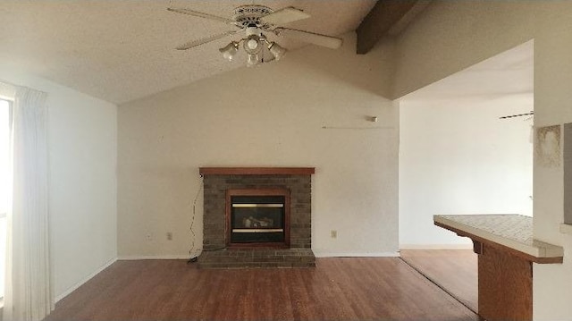 unfurnished living room with a brick fireplace, lofted ceiling with beams, hardwood / wood-style floors, and ceiling fan