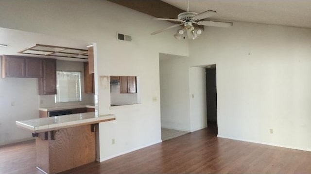 kitchen featuring lofted ceiling, tile counters, dark hardwood / wood-style flooring, kitchen peninsula, and ceiling fan