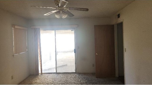 carpeted spare room featuring a textured ceiling and ceiling fan