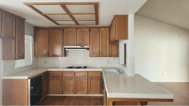 kitchen featuring sink, backsplash, tile counters, black cooktop, and kitchen peninsula