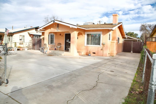 view of front of home featuring a gate, a chimney, fence, and stucco siding