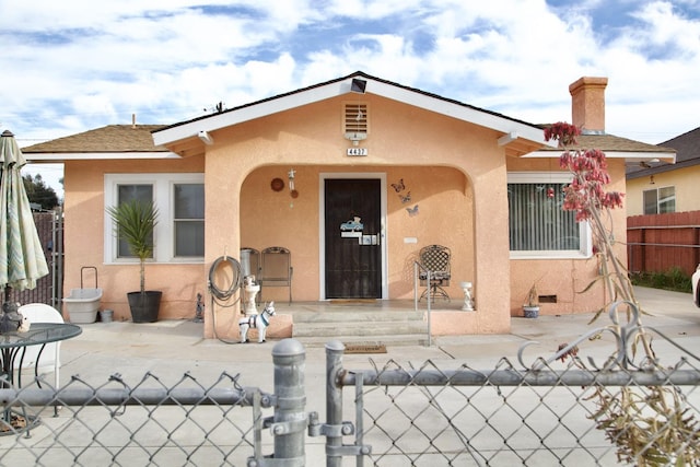 bungalow-style house with a patio, fence, a gate, and stucco siding