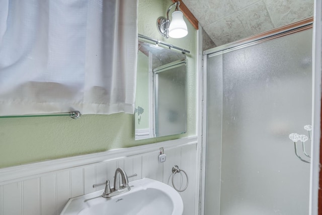 bathroom featuring a shower with door and sink