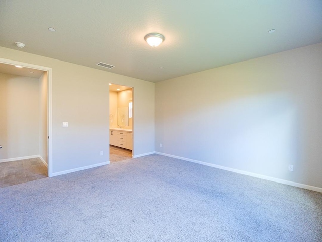 unfurnished bedroom featuring light colored carpet and connected bathroom