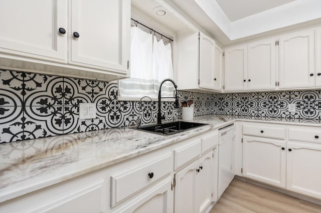 kitchen with dishwasher, sink, and white cabinets