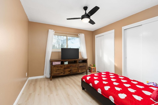 bedroom with ceiling fan, light hardwood / wood-style floors, and multiple closets